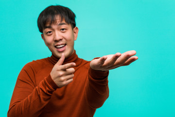 Young chinese man holding something with hand