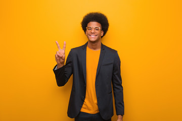 Young business african american man over an orange wall showing number two