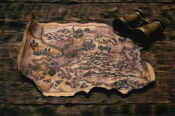 Wall Mural - Old map and binoculars on a adventurer table background. Treasure hunt concept.