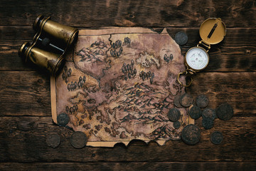 Wall Mural - Old map, compass and binoculars on a adventurer table background. Treasure hunt concept.