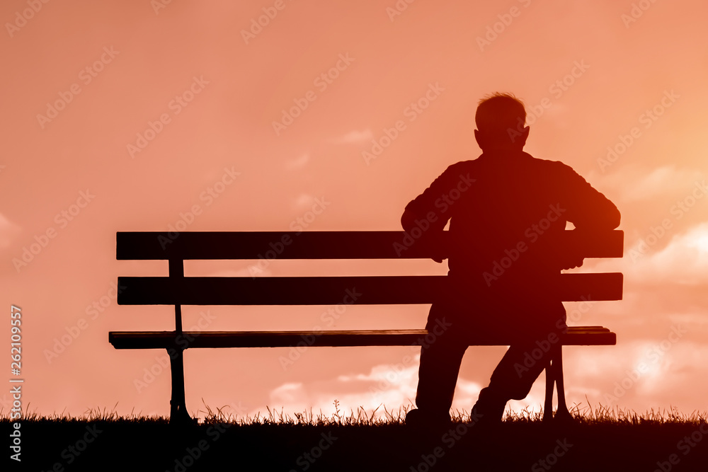 old man sitting alone on park bench under tree; - obrazy, fototapety, plakaty 