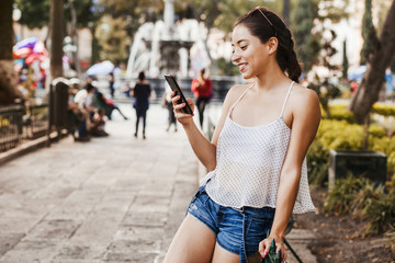 young latin woman messaging by phone wearing casual clothes in Mexico