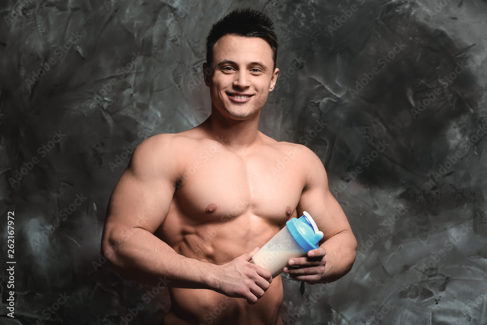 Sporty man with protein shake on grunge background