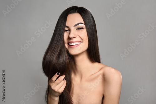 Fotomural Portrait of beautiful young woman with healthy long hair on grey background
