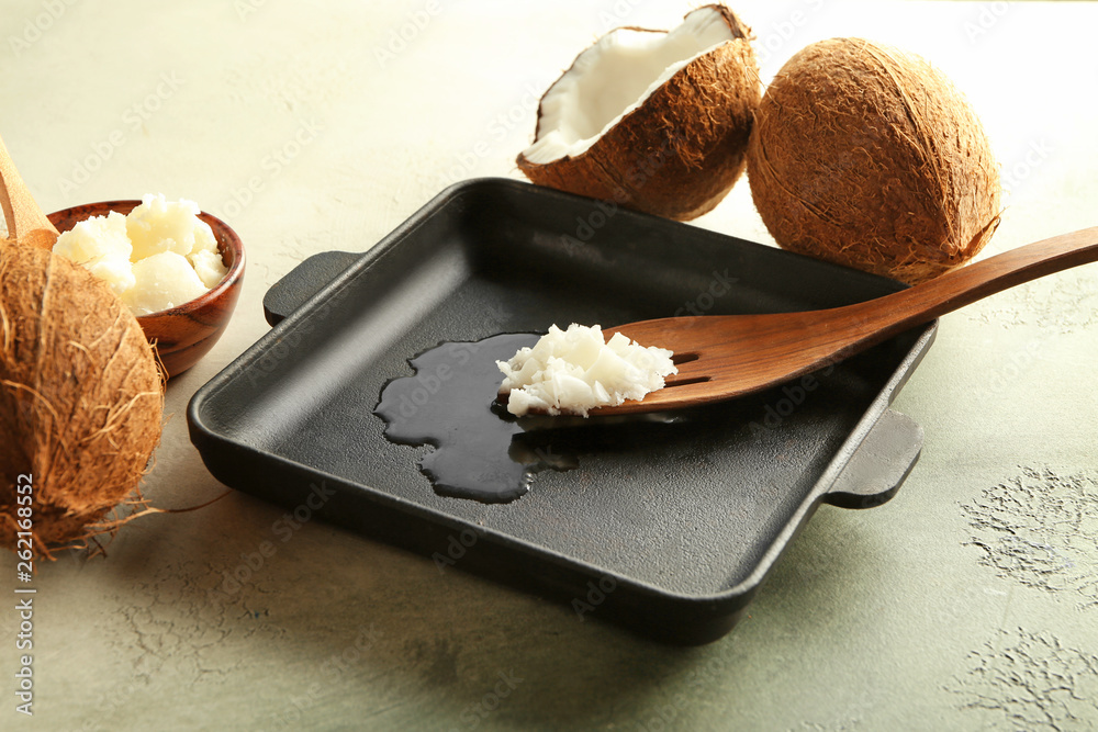 Frying pan with coconut oil on light background