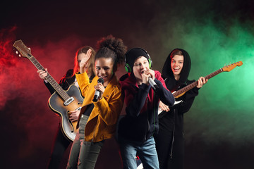 Wall Mural - Band of teenage musicians on dark background