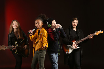 Wall Mural - Band of teenage musicians on dark background