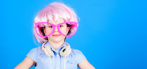 Synthetic hair. Cool little child with pink hair wig. Adorable small girl with fancy hair style wearing headphones. Beauty look of crazy hair model, copy space