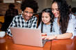 © leszekglasner - Happy multiethnic family having fun while using laptop together at restaurant