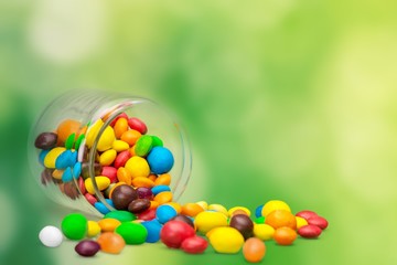 Wall Mural - Colorful candies sweets falling out of a glass jar, composition isolated over the white background