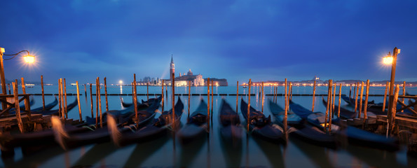 Wall Mural - A row of gondolas parking beside the San Marco Place at sunrise with a curch San Giorgio di Maggiore as a background in Venice, Italy