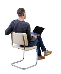 Canvas Print - Back view of a man who sits on a chair with a laptop.