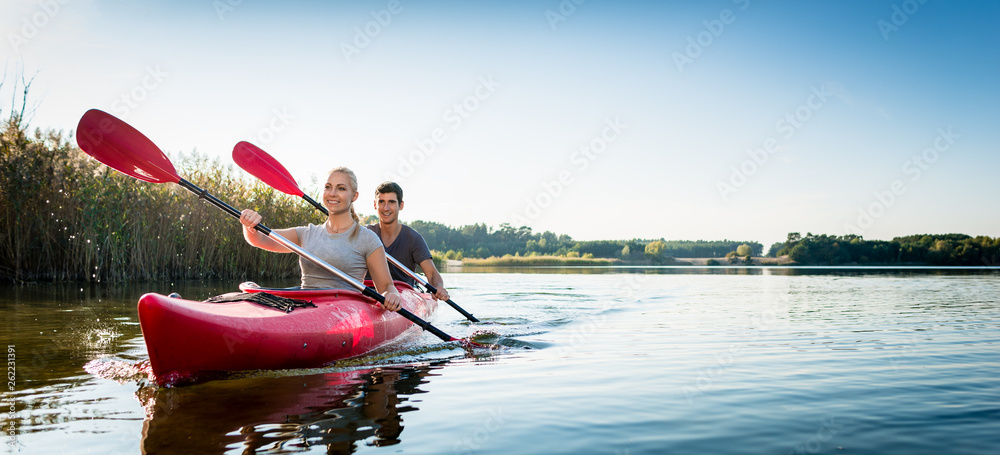 Beautiful couple sailing kayak on lake - obrazy, fototapety, plakaty 