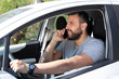 © nikodash - Man talking at mobile phone while driving a car.