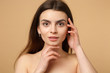 © ViDi Studio - Close up brunette half naked woman 20s with perfect skin, hands on face isolated on beige pastel wall background, studio portrait. Skin care healthcare cosmetic procedures concept. Mock up copy space.