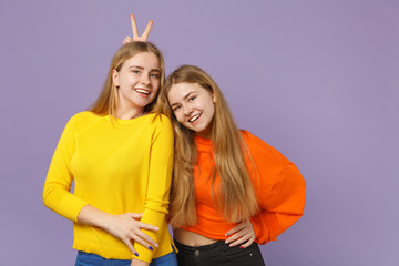 Two smiling young blonde twins sisters girls in vivid colorful c