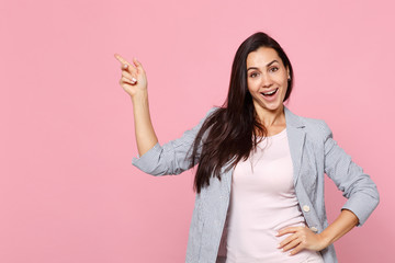 Wall Mural - Portrait of cheerful pretty young woman in striped jacket pointing index finger aside up isolated on pink pastel background in studio. People sincere emotions, lifestyle concept. Mock up copy space.