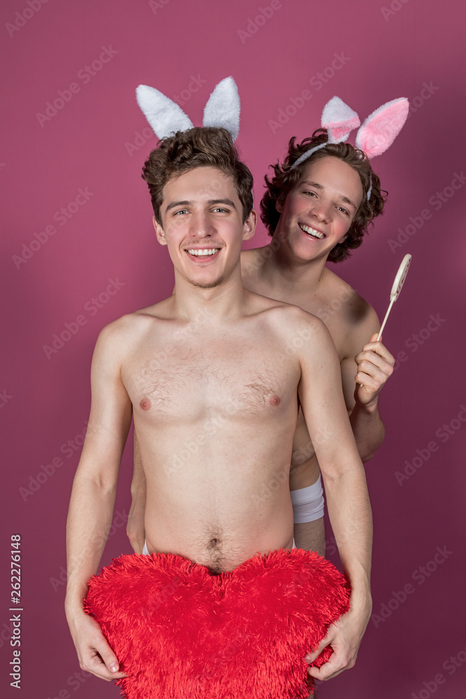Two funny naked guys wearing bunny ears holding lollipop and big red