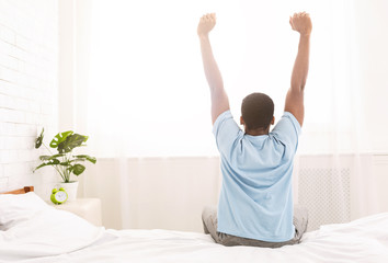 Wall Mural - Young man waking up in bed and stretching his arms