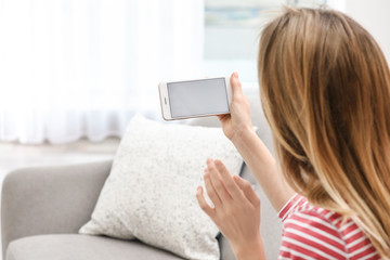 Poster - Young woman using video chat on smartphone in living room, closeup. Space for design