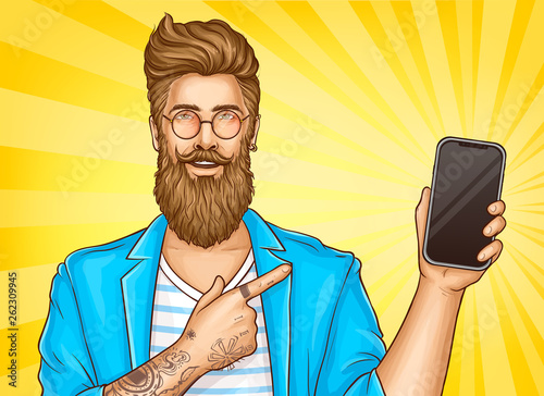 Fotografie, Obraz Bearded hipster man with tattoos wearing fashioned clothing and round glasses point with index finger on smartphone in other hand