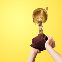 Hands holding golden trophy on light background