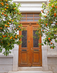 vintage house entrance wooden door and orange trees, athens greece