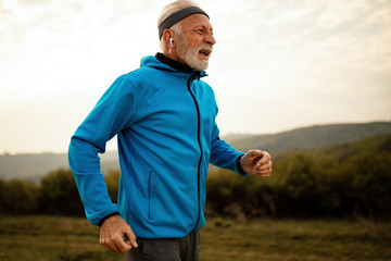 Determined senior man running in nature in the morning.