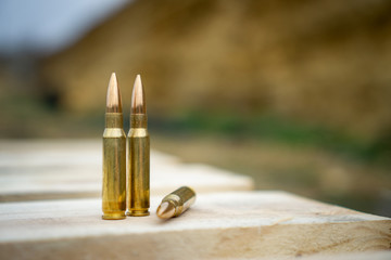 308 caliber ammunition for a rifle standing on a wooden table on the background of the shooting range