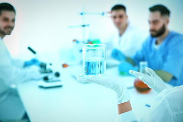 Medical student with beaker working in scientific laboratory, color tone