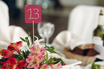 Cute handmade table number close-up at wedding reception in luxury restaurant, table number sign on flowers bouquet at restaurant wedding party