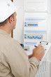 © auremar - electrician worker checking clipboard while working in fuse-board