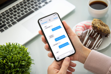 female hands holding phone with app messenger on the screen