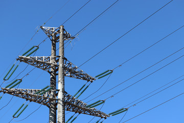 High voltage power line support with electrical wires on background of clear blue sky. Electricity transmission lines, power supply concept