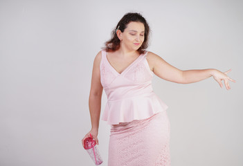 Wall Mural - chubby woman in pink dress with glass of water on white background in Studio