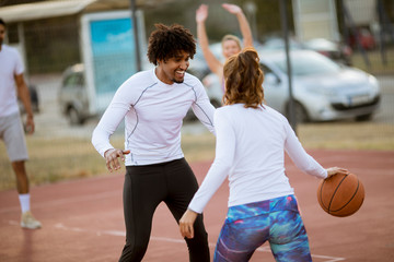 Group of multiethnic people  playing basketball on court