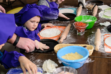 Wall Mural - Children make pizza. Master class for children on cooking Italian pizza. Young children learn to cook a pizza. Kids preparing homemade pizza