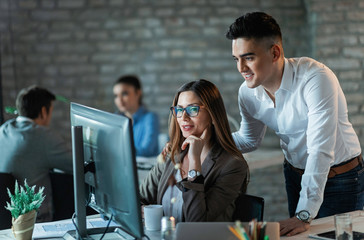 Happy business couple working together on a computer in the office.