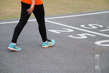 Closeup of Asian woman walking in running track.