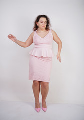 Wall Mural - pretty chubby positive girl dancing in pink fashionable dress on white studio background