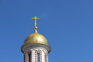 Golden dome of the Christian temple with a cross against the clear blue sky. Orthodox church, background for Easter greeting card