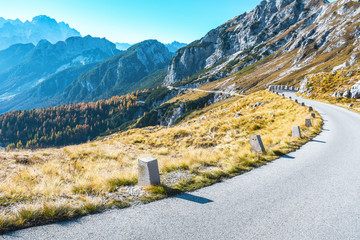 Old military road headed to Mangart saddle high in Julian alps on a sunny beautiful autumn day with colorful scenery and surrounded with mountain peaks