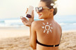 © verona_studio - Woman Applying Sun Cream  on Tanned  Shoulder In Form Of The Sun. Sun Protection.Sun Cream. Skin and Body Care. Girl Using Sunscreen to Skin. Female Holding Suntan Lotion and Moisturizing Sunblock.