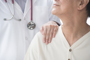 Medical doctor reassuring senior patient and putting a hand on patient’s shoulder