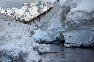 Canvas Print - pieces of snow from the mountain avalanche in the river against the backdrop of mountain peaks, the Gonachkhir river Karachay-Cherkess Rep. Russia