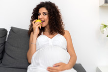 Pregnant Woman Eating Apple And Smiling