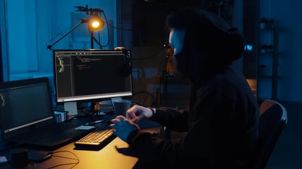 Poster - cybercrime, hacking and technology concept - asian male hacker in mask using computer for cyber attack and taking notes in dark room at night