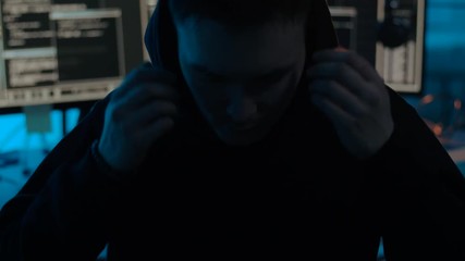 Poster - cybercrime, hacking and technology concept - young asian hacker taking his hood off in dark room with computers at night