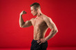 © Alexandr - handsome young man in athletic form on red background shows his muscles
