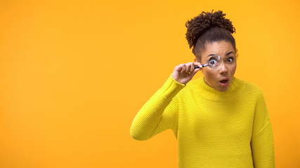 Teenage female looking magnifying glass, shocked and surprised by information